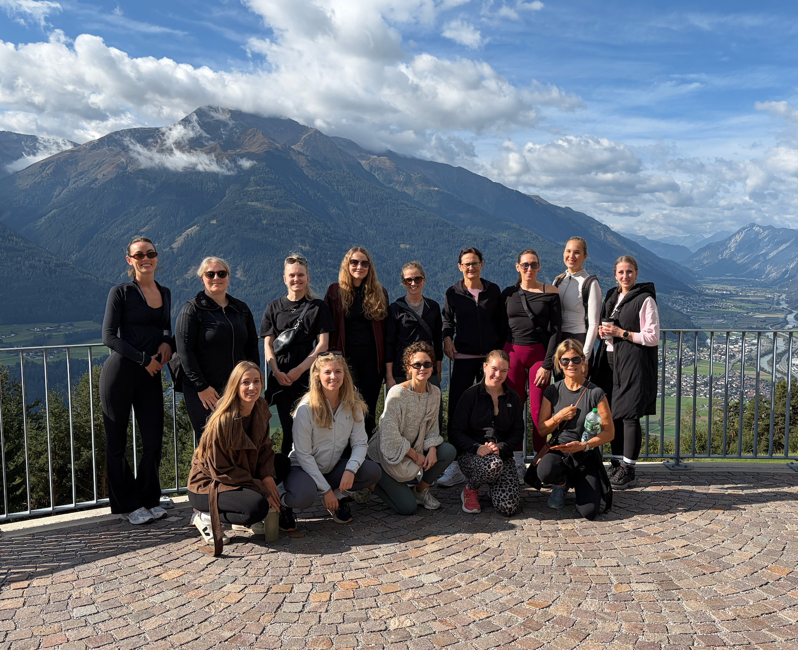Die The Pilates Reset Community gemeinsam auf der Aussichtsplattform vor Bergpanorama